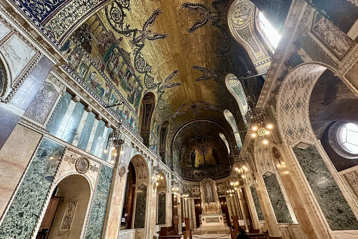 A vault covered in gold mosaic above marble piers and arches in the Lady Chapel of Westminster Cathedral.